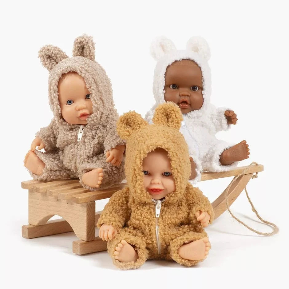 Three dolls in bear costumes sitting on a wooden seesaw against a white background