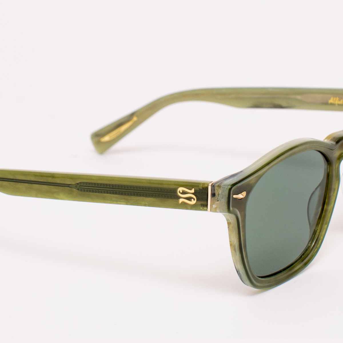 Green sunglasses with gold accents on a white background