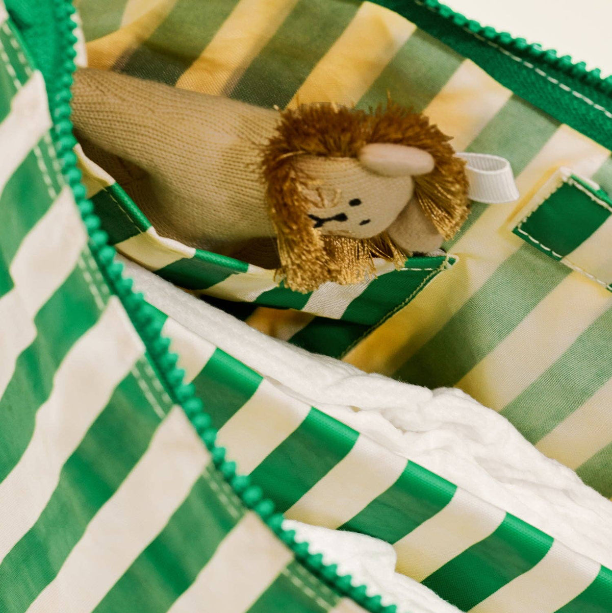 Toy lion inside a green and white striped bag