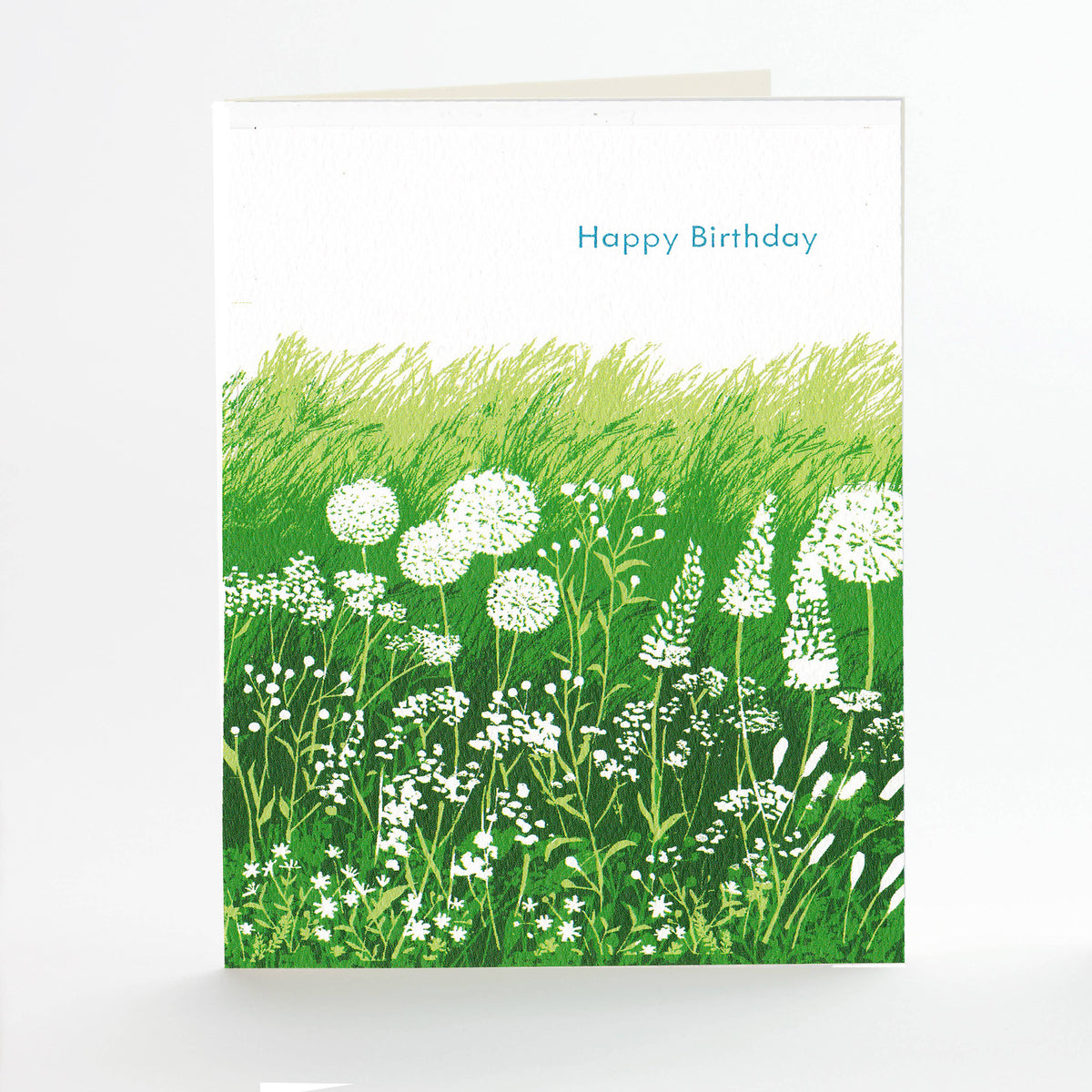 Greeting card with a field of green grass and white flowers, and 'Happy Birthday' text.