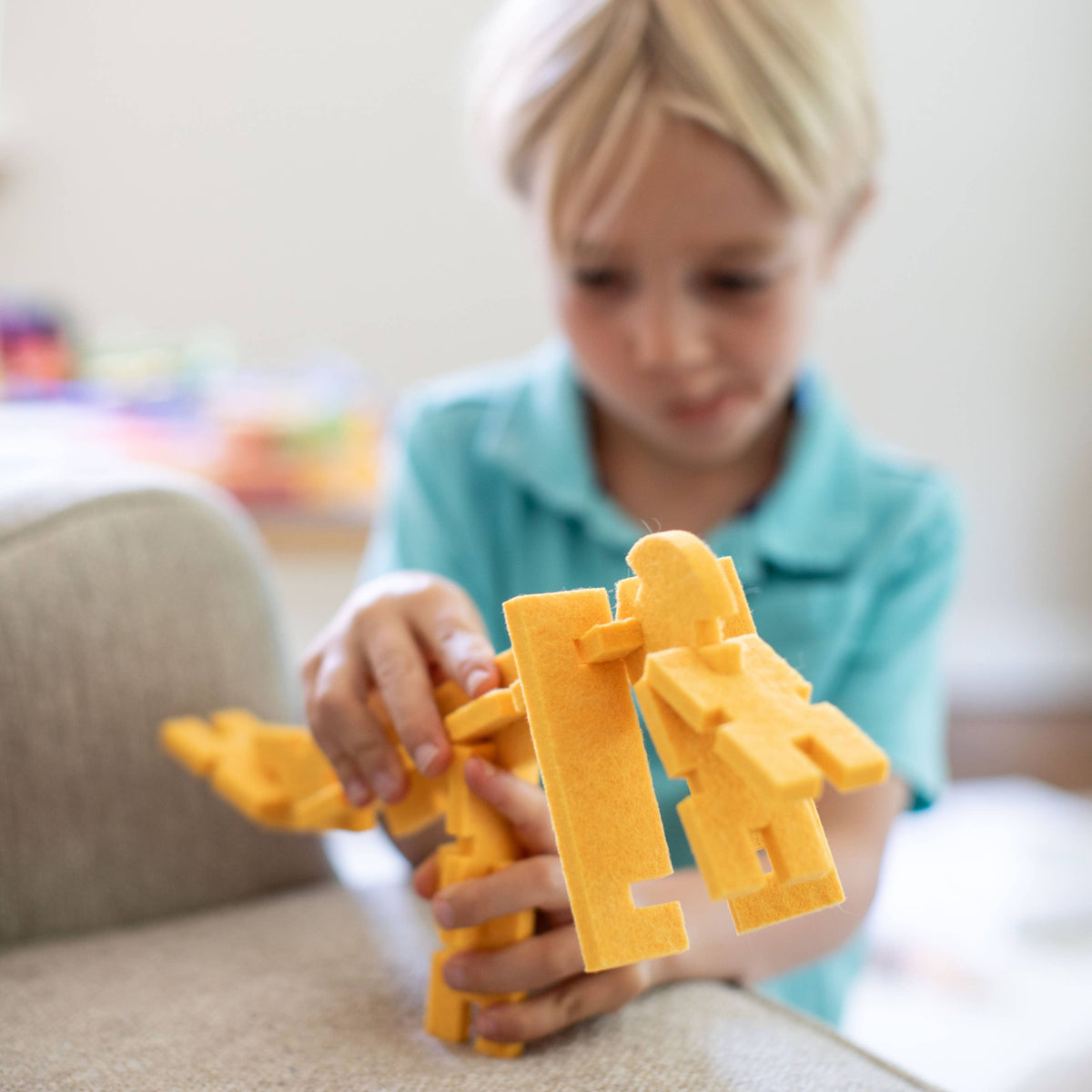 Child playing with yellow felt pieces on a couch