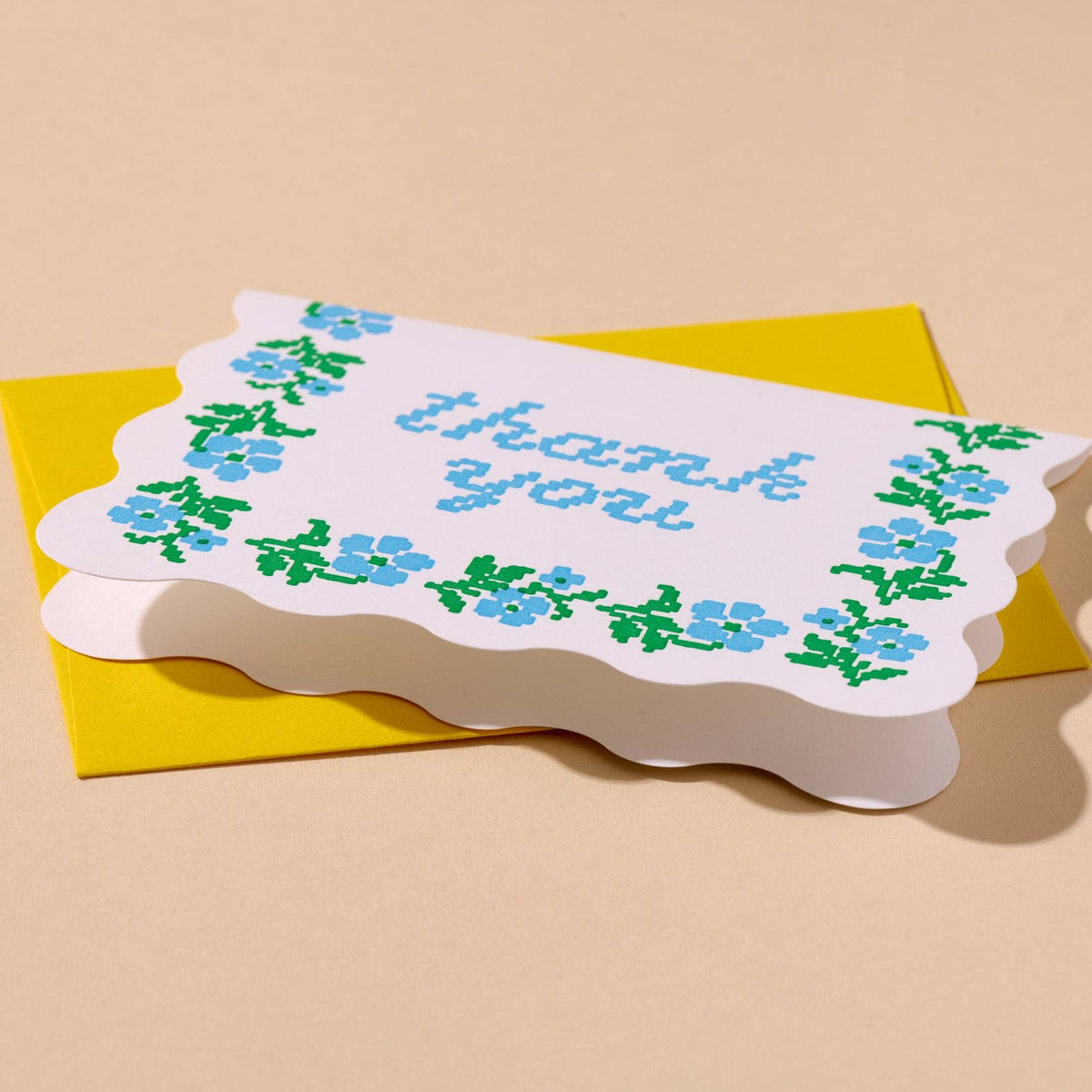 Greeting card with floral design and 'thank you' text on a beige background