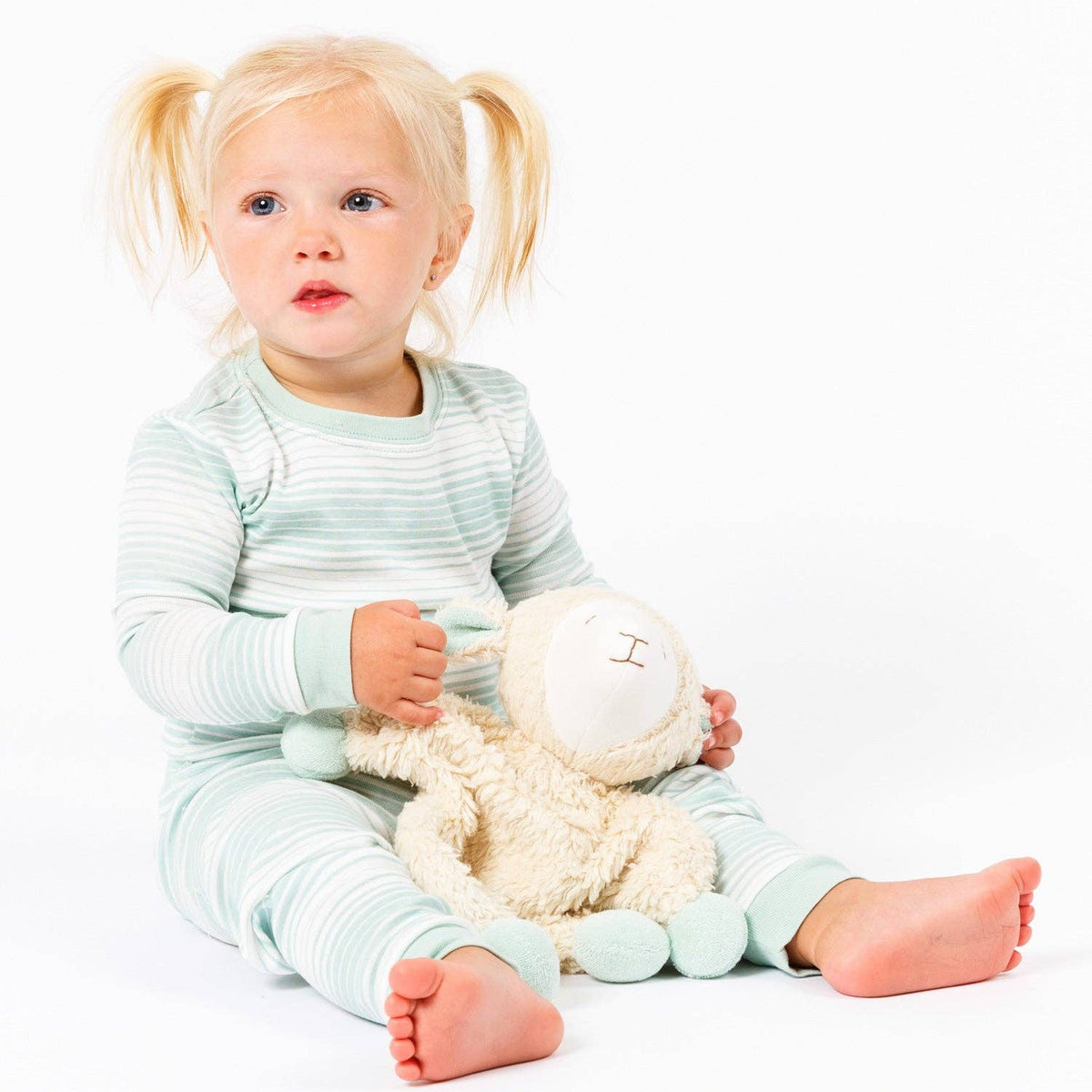 Child in striped pajamas holding a plush toy on a white background