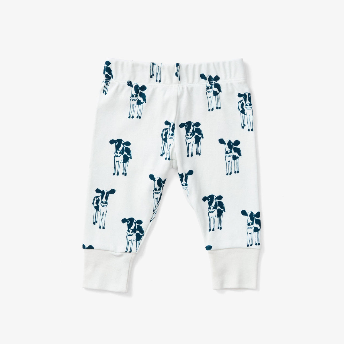 White baby jogger pants with an all-over navy blue cow print and ribbed ankle cuffs, shown flat on a light gray background.