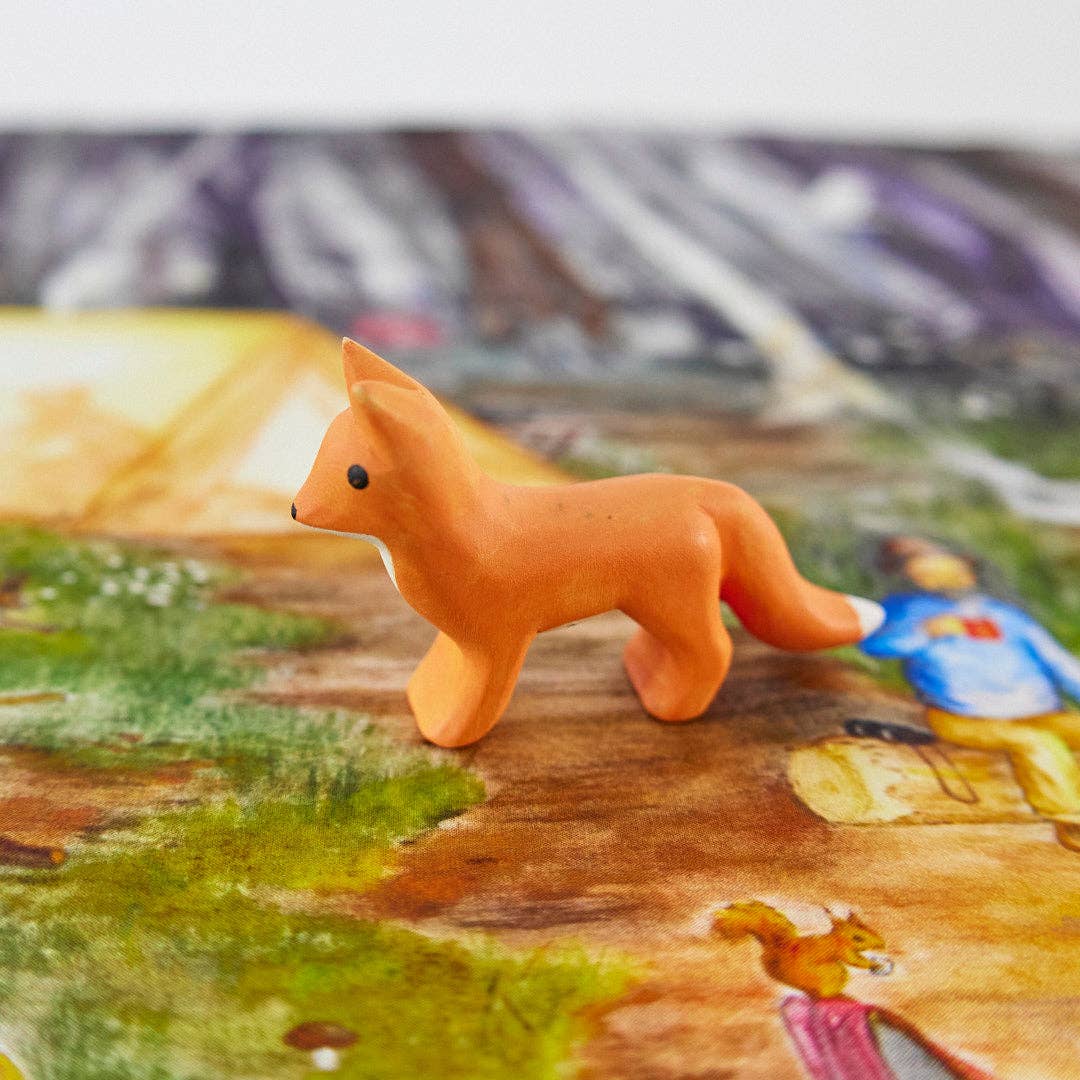 A small orange fox figurine with a white chest and black eyes, standing on a plain white background.
