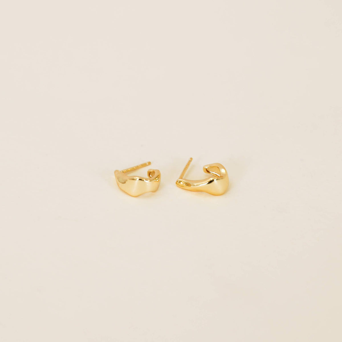 Gold hoop earrings on a beige background