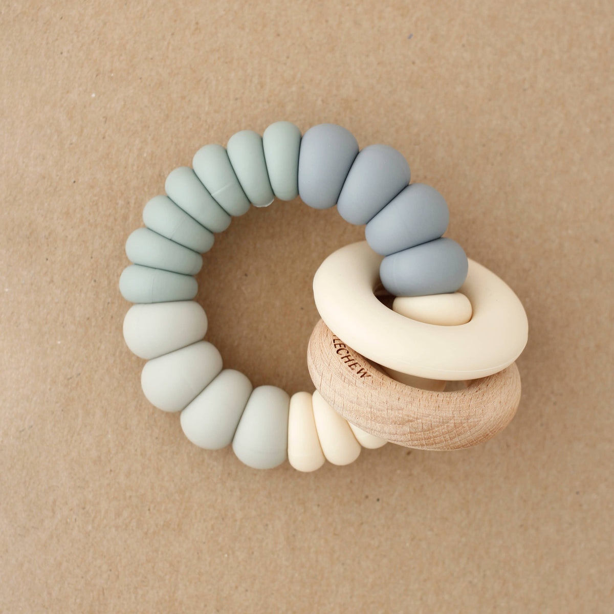 Teething ring with silicone and wooden beads on a beige background
