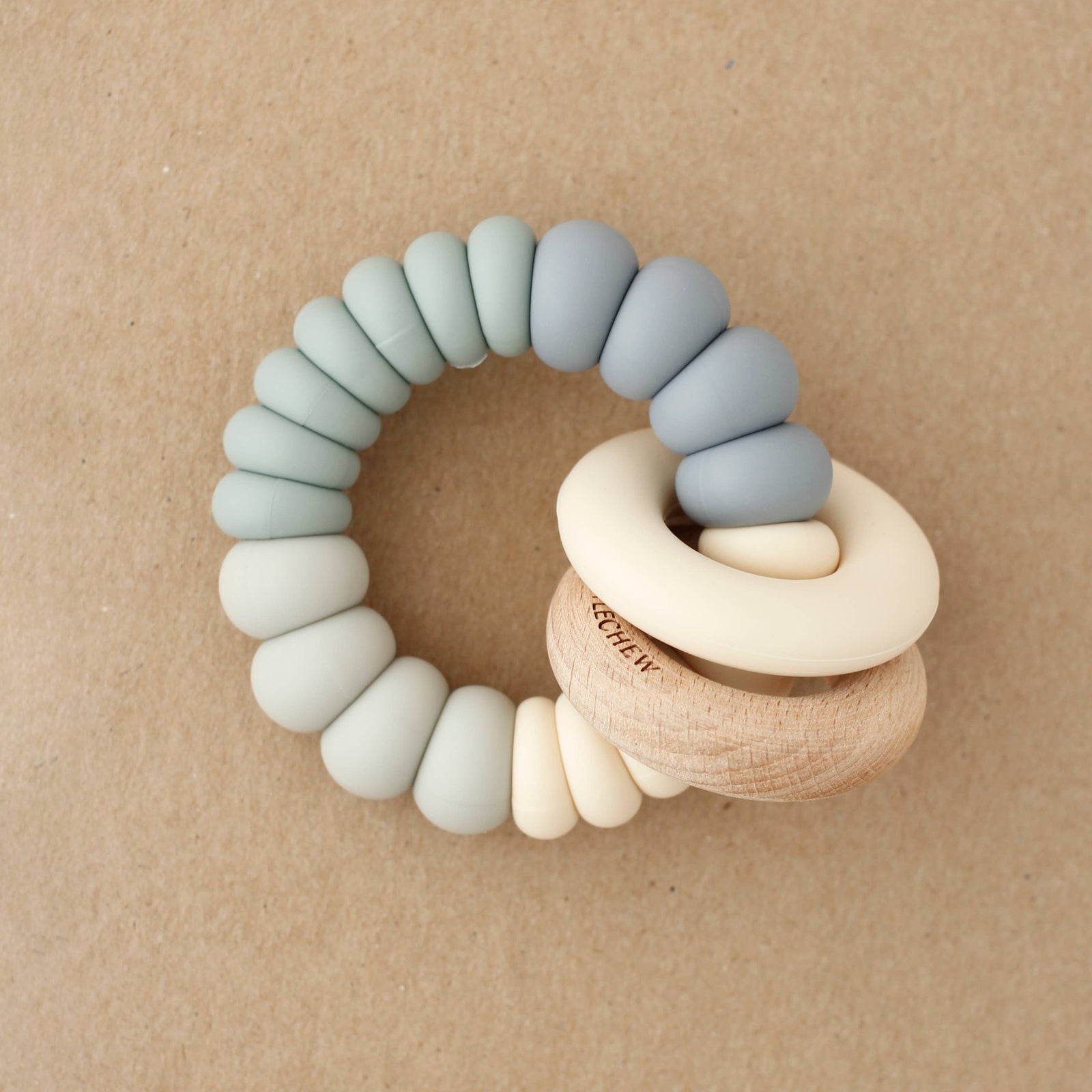 Teething ring with silicone and wooden beads on a beige background