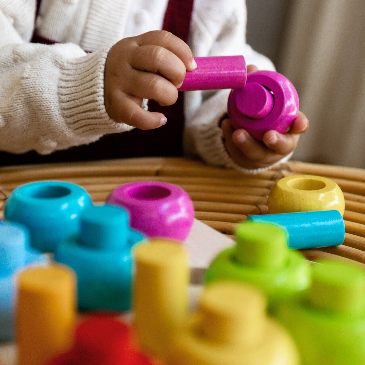 Child playing with colorful building blocks on a wooden surface