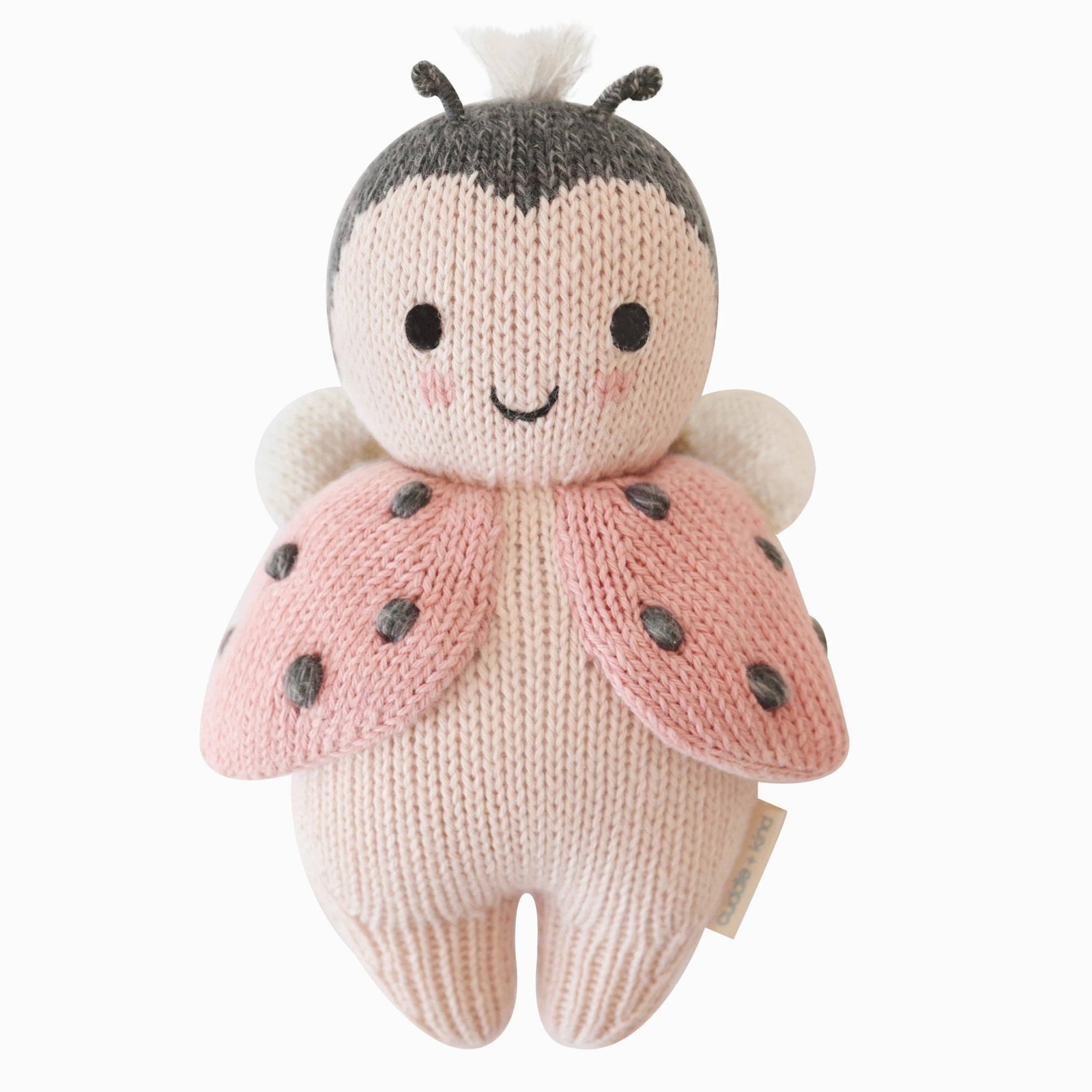 Knitted ladybug toy with pink wings and black spots on a white background