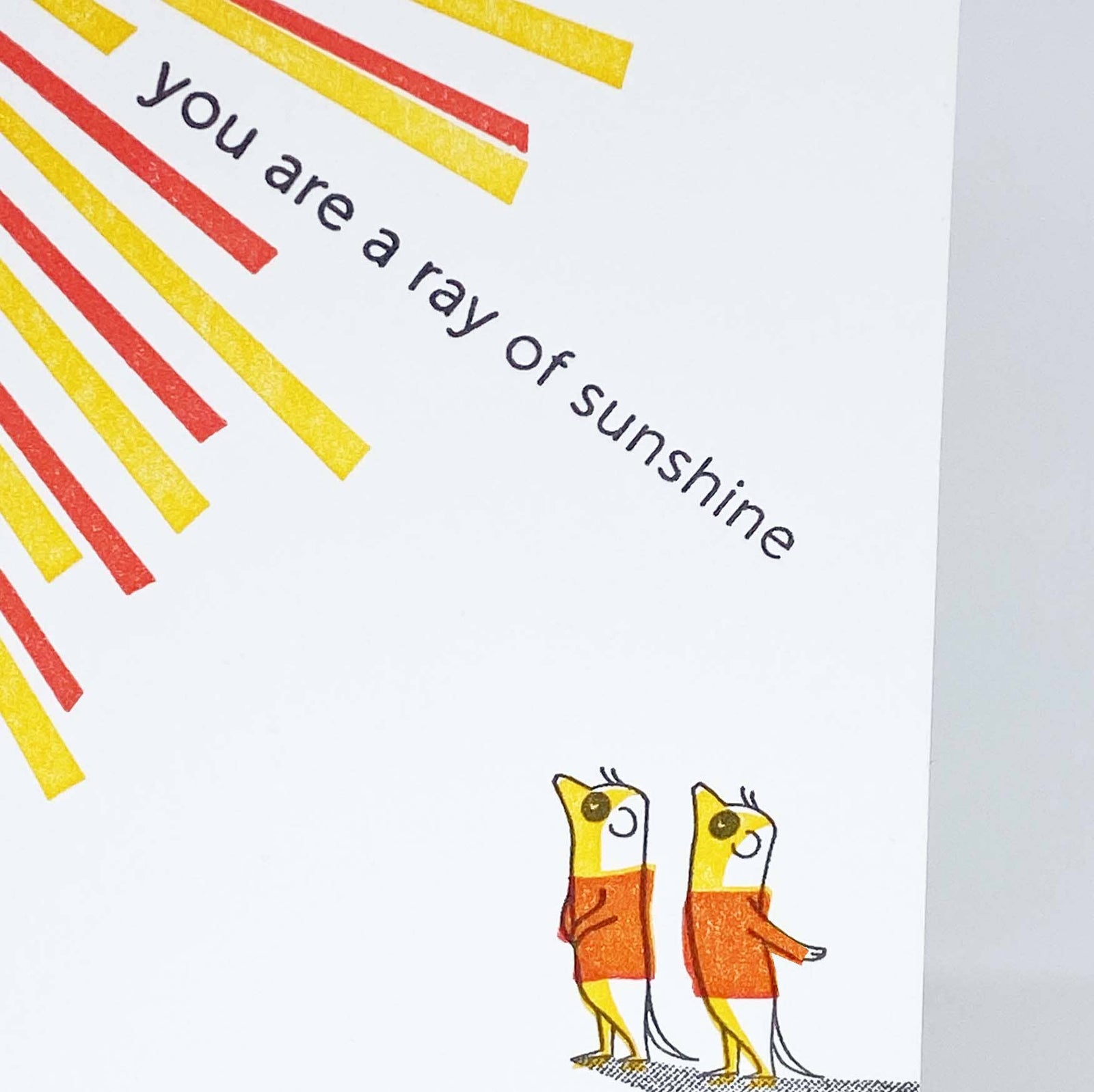 Greeting card with sunburst design and birds on a branch, featuring the text 'you are a ray of sunshine'.