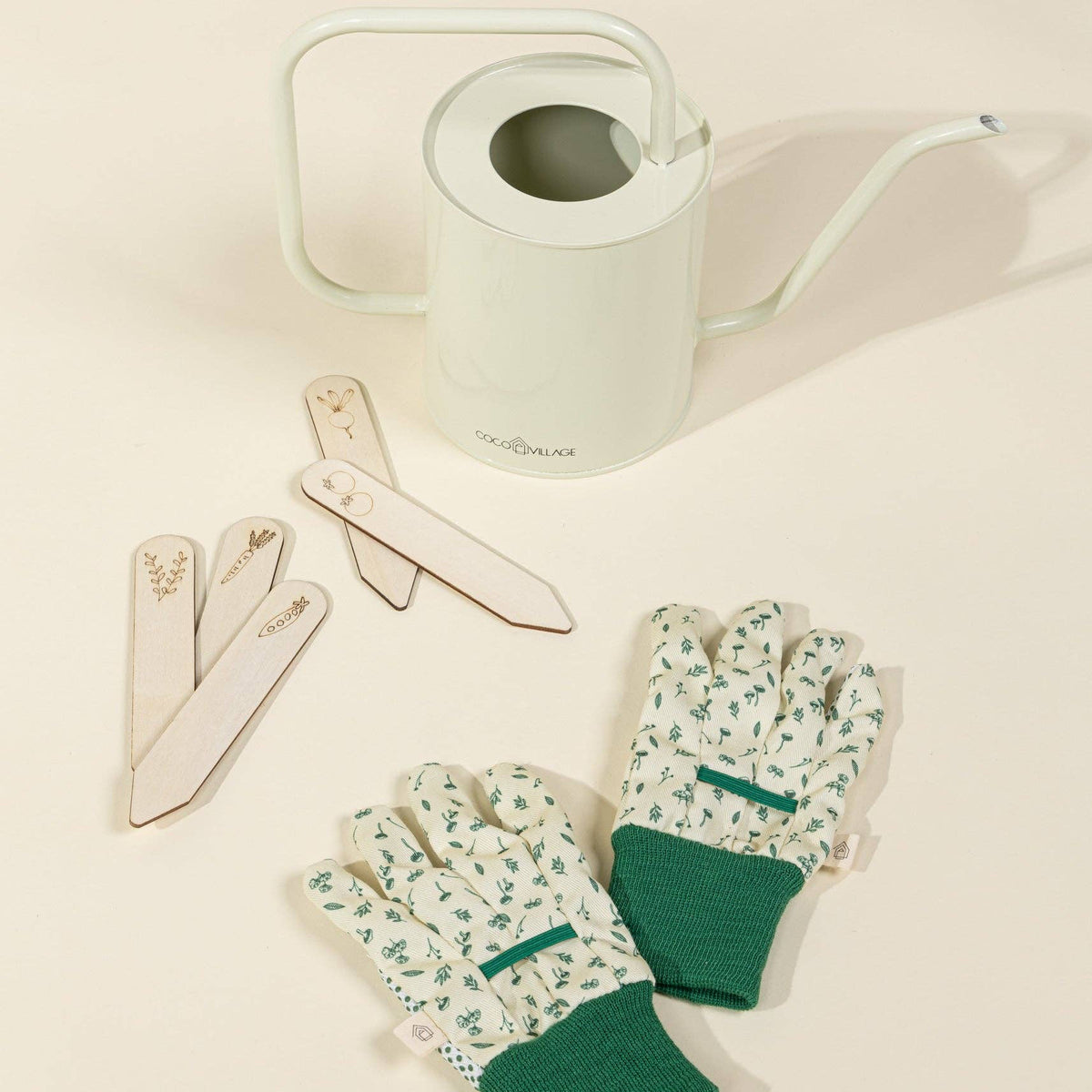 Gardening tools including gloves, labels, and a watering can on a light background