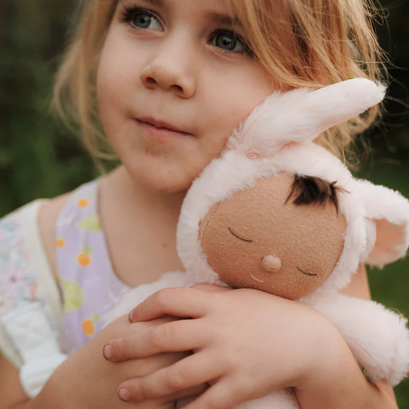 Child holding a plush toy with a blurred green background