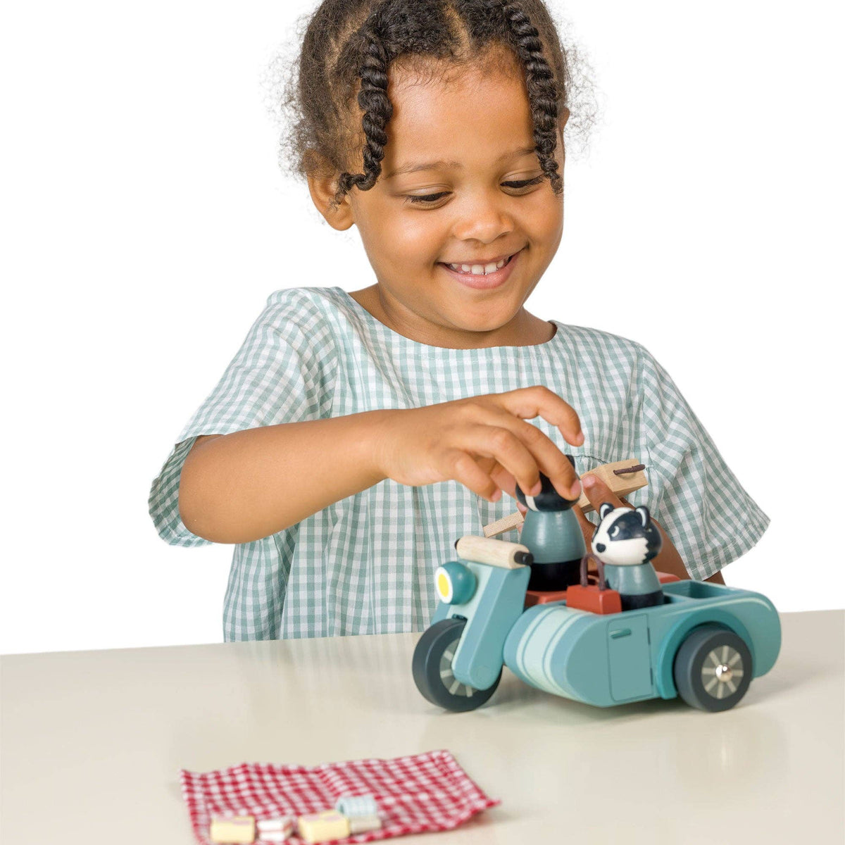 Child playing with a toy car and figure on a white surface