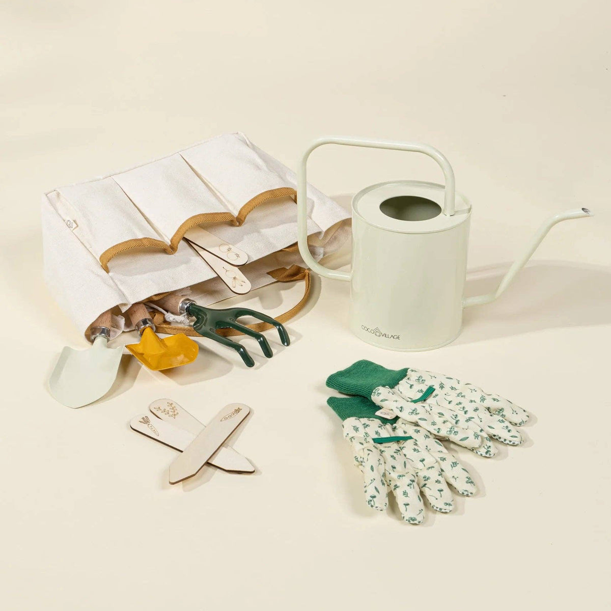 Gardening tools including a watering can, trowel, and gloves on a beige background