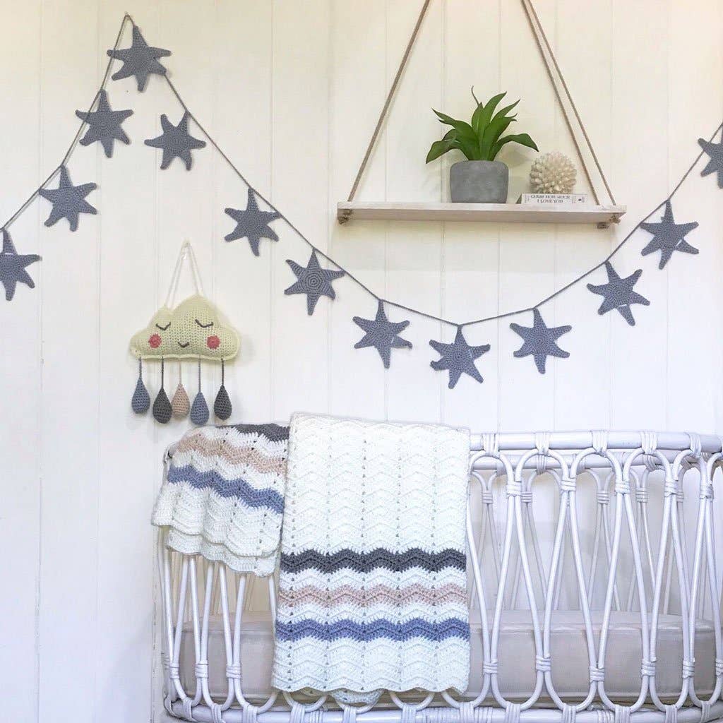 Nursery room with star-shaped decorations, a crib, and a shelf with plants.