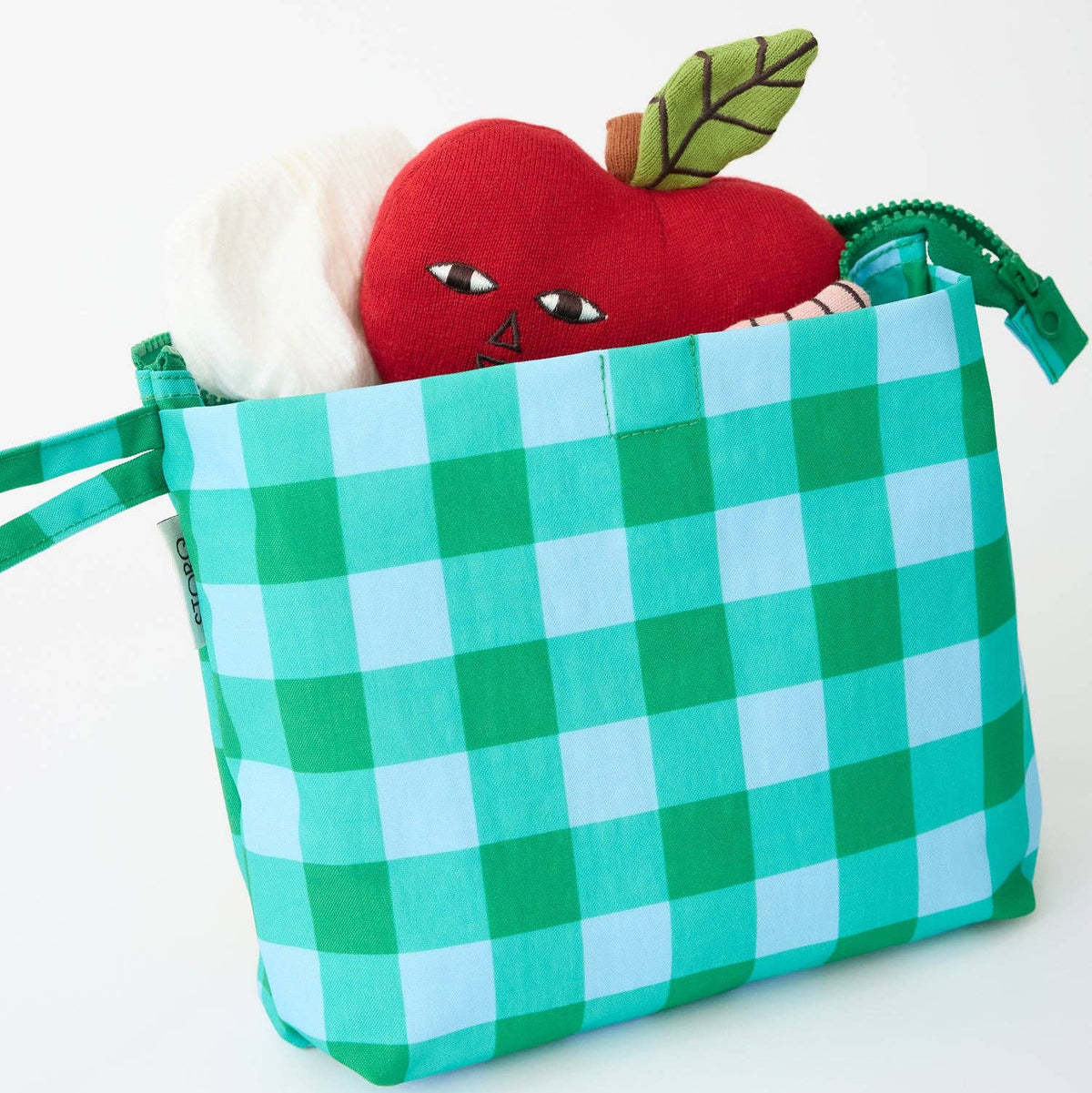 A green and light blue gingham fabric storage bag with a zipper, shown on a white background with a red apple plush toy and a white plush item peeking out from inside.