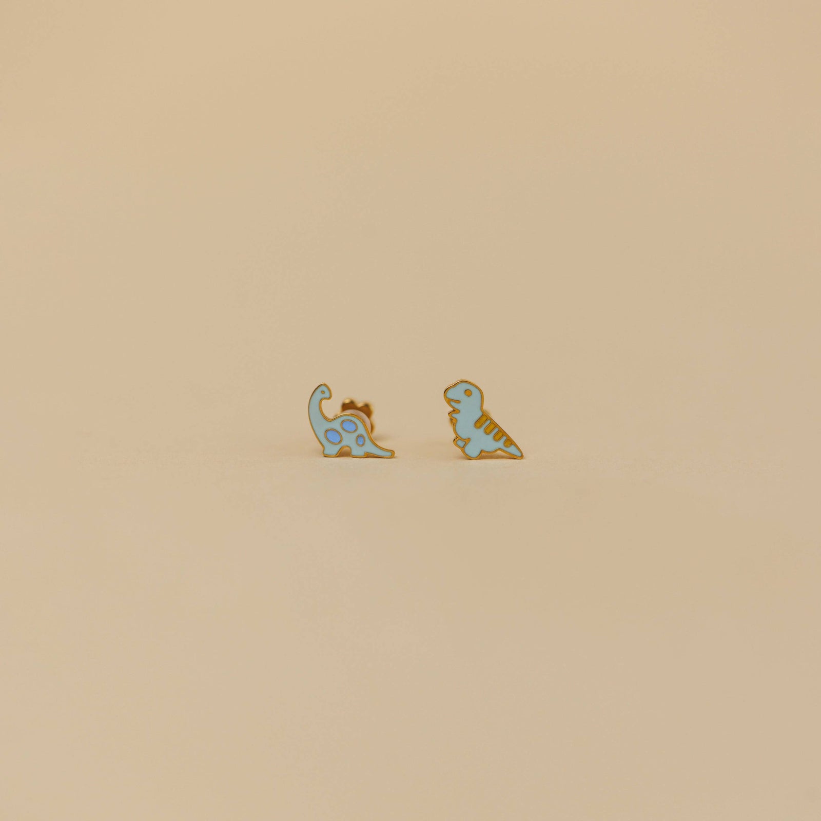 Small card with dinosaur earrings on a beige background