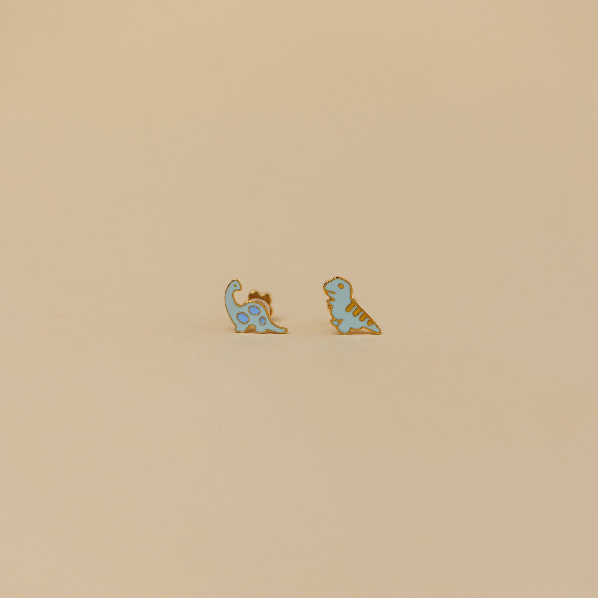 Small card with dinosaur earrings on a beige background