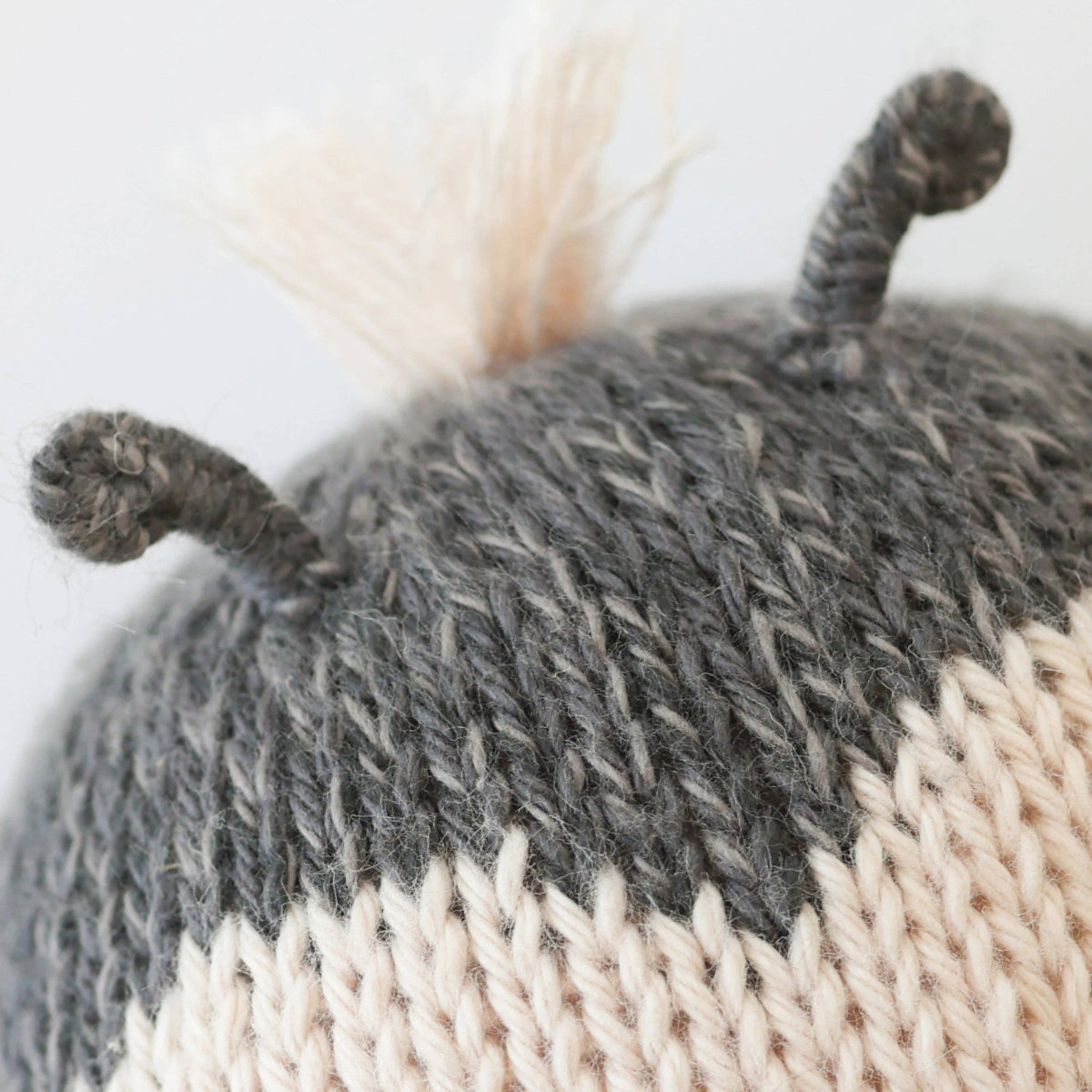 Close-up of a knitted hat with gray and beige pattern on a white background