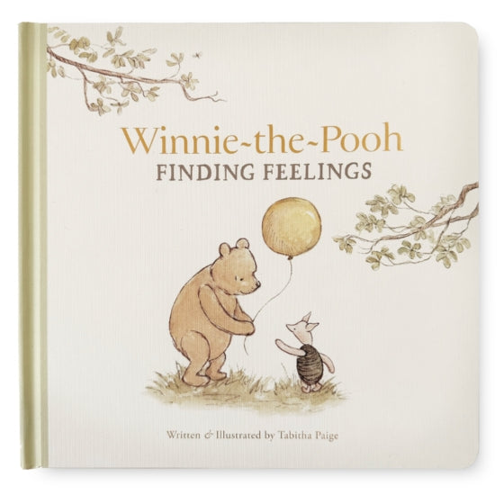 The front cover of the children's board book 'Winnie-the-Pooh Finding Feelings' by Tabitha Paige. The cover features a warm cream background with a textured linen-like pattern, gold foil title lettering, and an illustration of Winnie-the-Pooh holding a gold balloon next to Tigger.