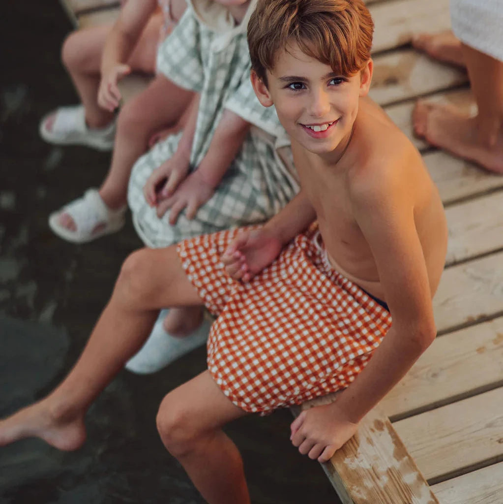 Children sitting on a wooden dock by the water
