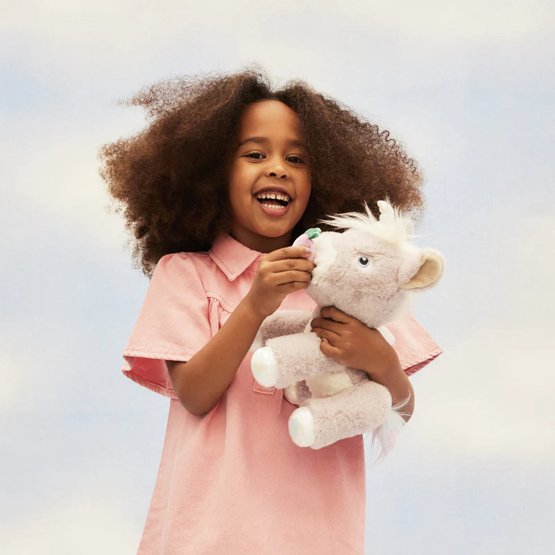 Child holding a stuffed animal unicorn against a light background