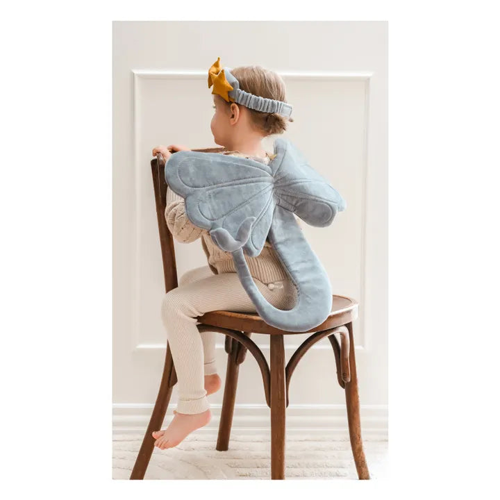 Child wearing a blue mermaid wing costume sitting on a chair.