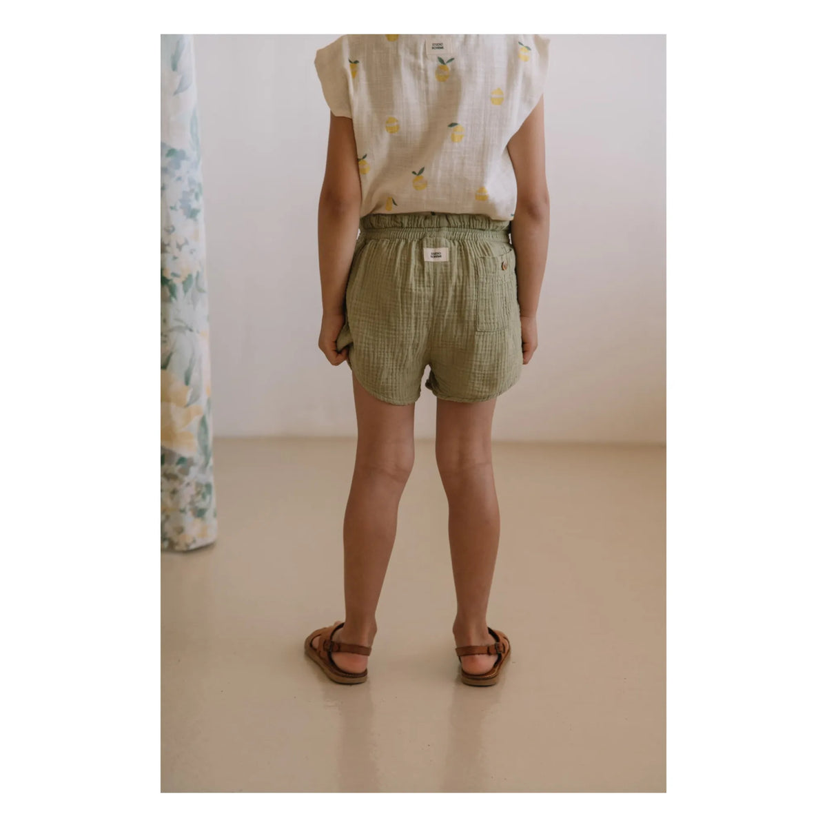 Person wearing green shorts and a white shirt with small patterns,