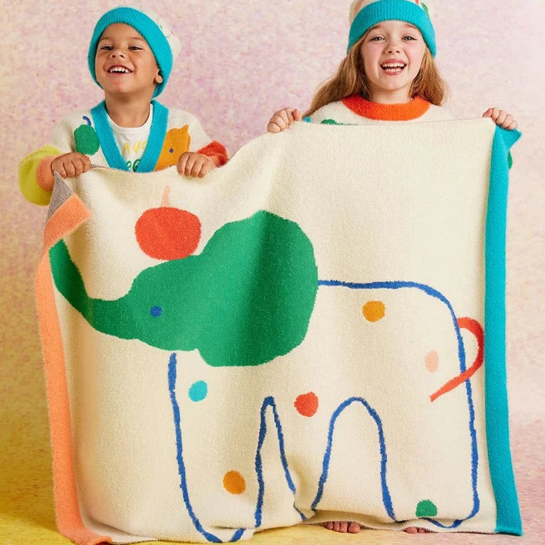 Two children holding up elephant print blanket