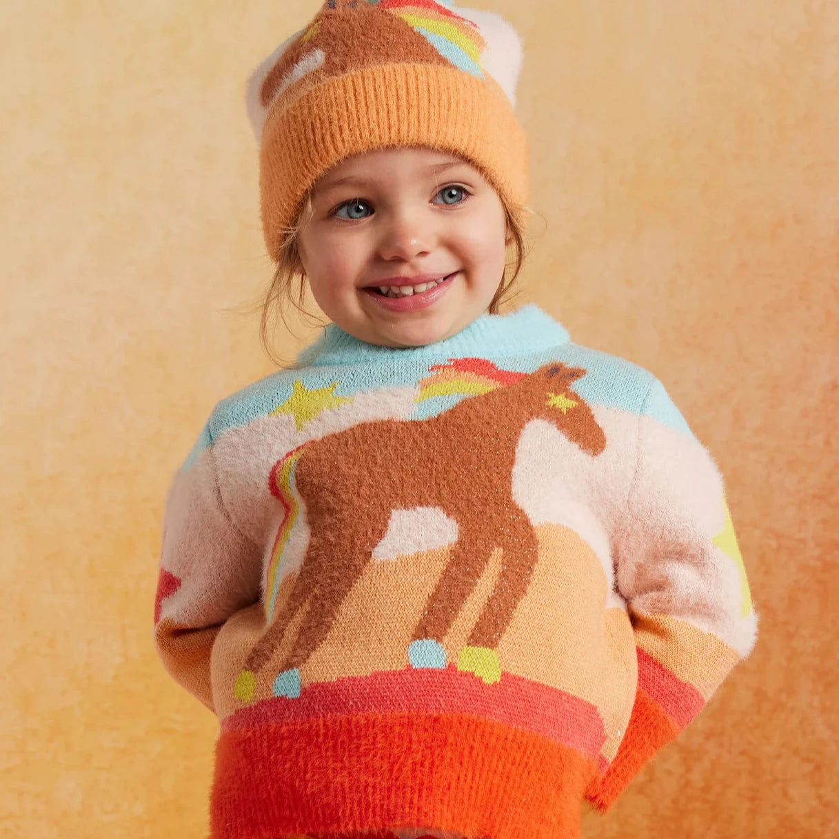 Child wearing horse print sweater in bright colors