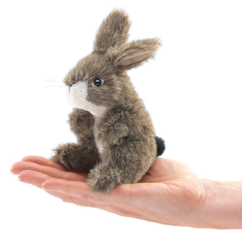Small brown plush rabbit held in a hand against a white background