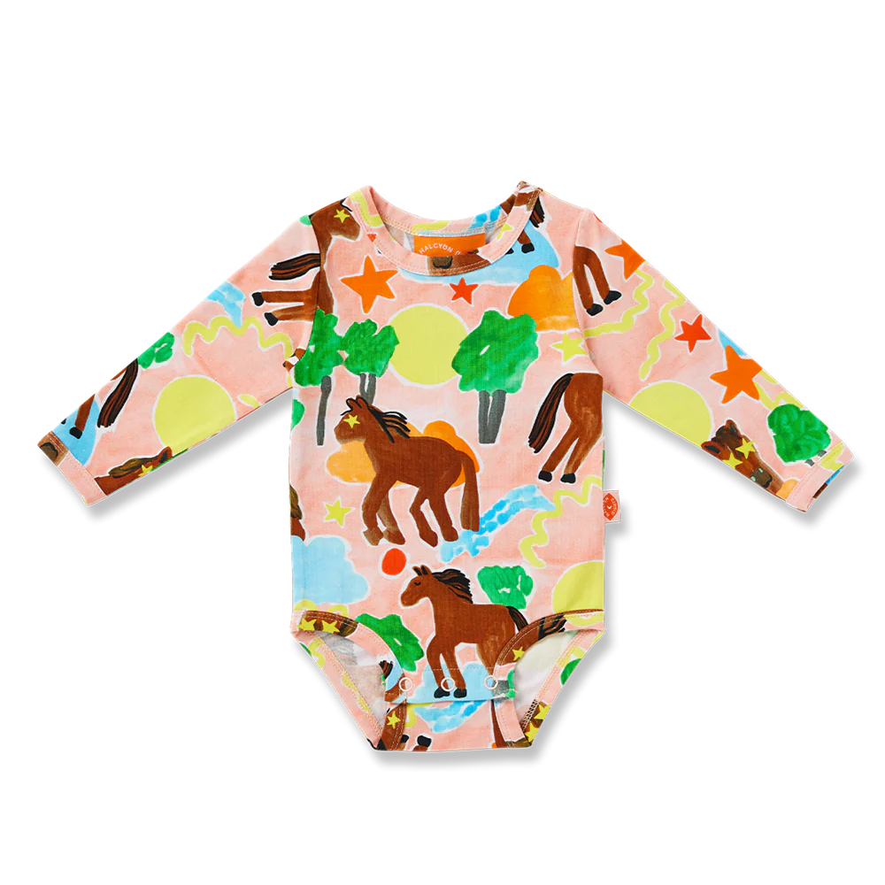 Child wearing a colorful onesie with animal prints on a soft background