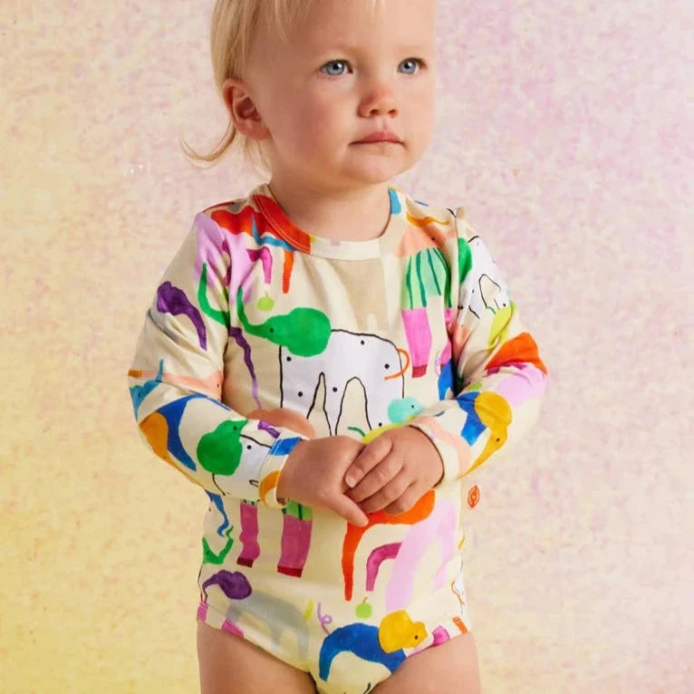 Child wearing a colorful onesie with animal prints on a soft background
