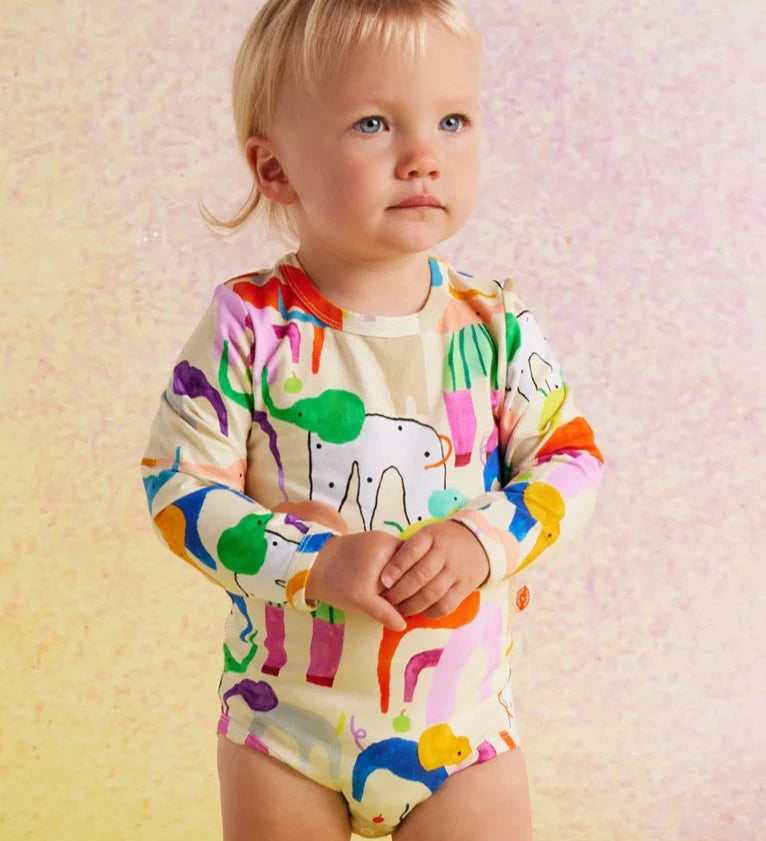 Child wearing a colorful onesie with animal prints on a soft background