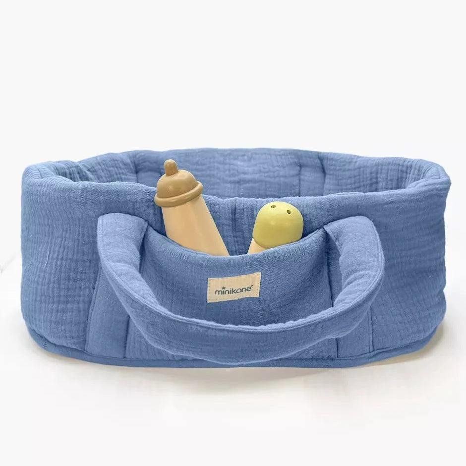 Blue baby doll bed with a bottle and toy on a white background