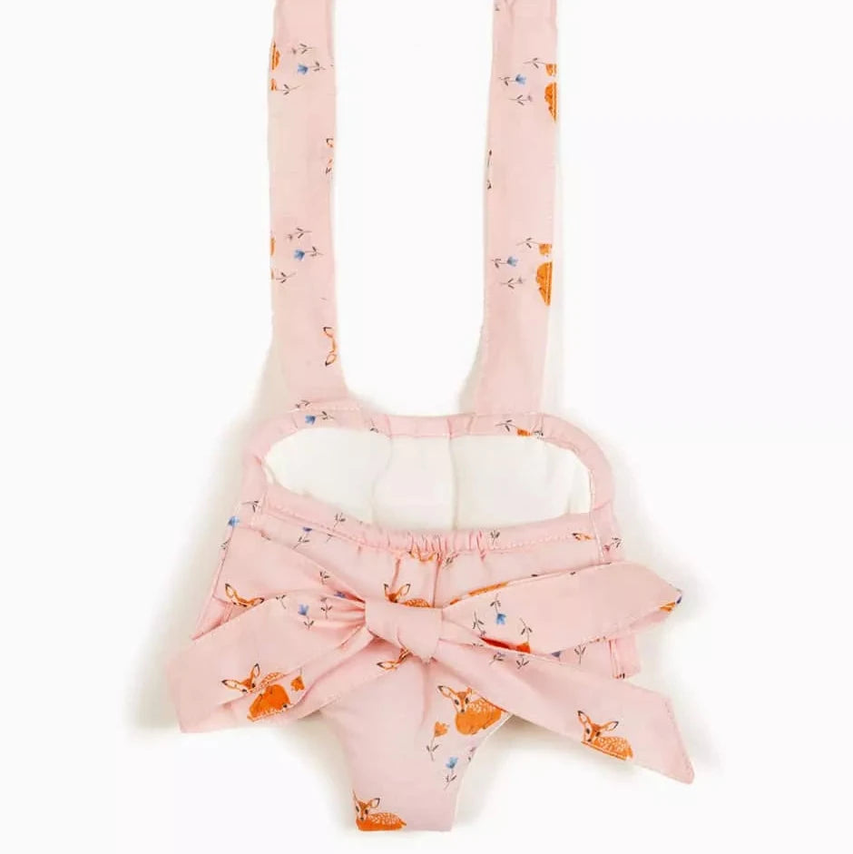 A pink fabric doll carrier with a matching bow, featuring an all-over print of orange deer and small blue flowers, shown against a plain white background.