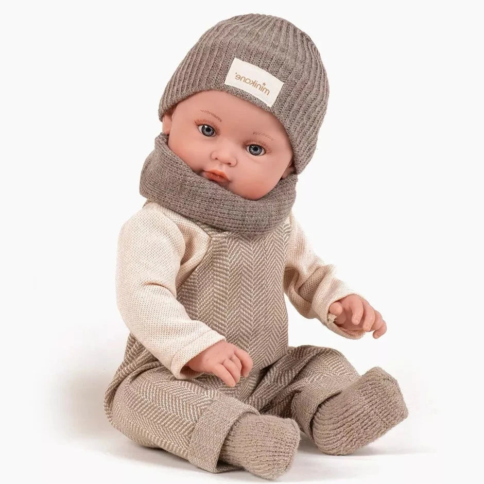 Baby doll wearing a beige knit outfit with a matching hat and scarf on a white background