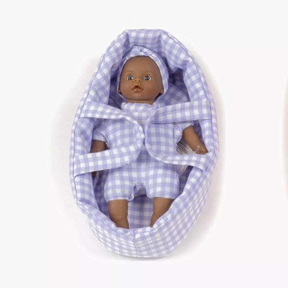 Baby doll in a purple checkered crib on a white background