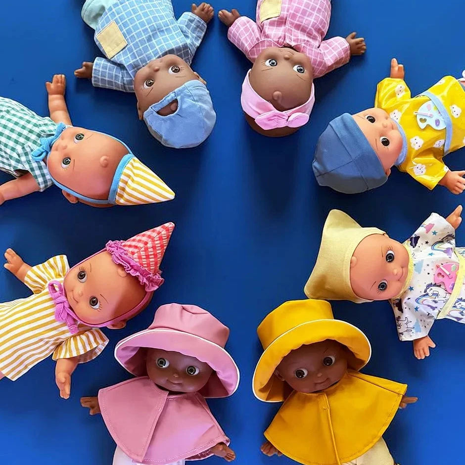 baby dolls arranged in a circle on a solid blue background, each wearing different colorful outfits in yellow, pink, blue, and green.