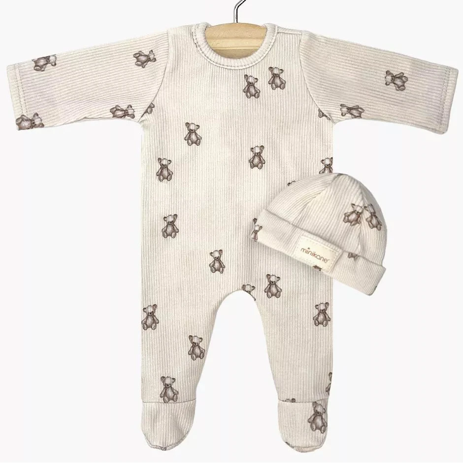 Toddler doll onesie and hat set with teddy bear pattern on a white background