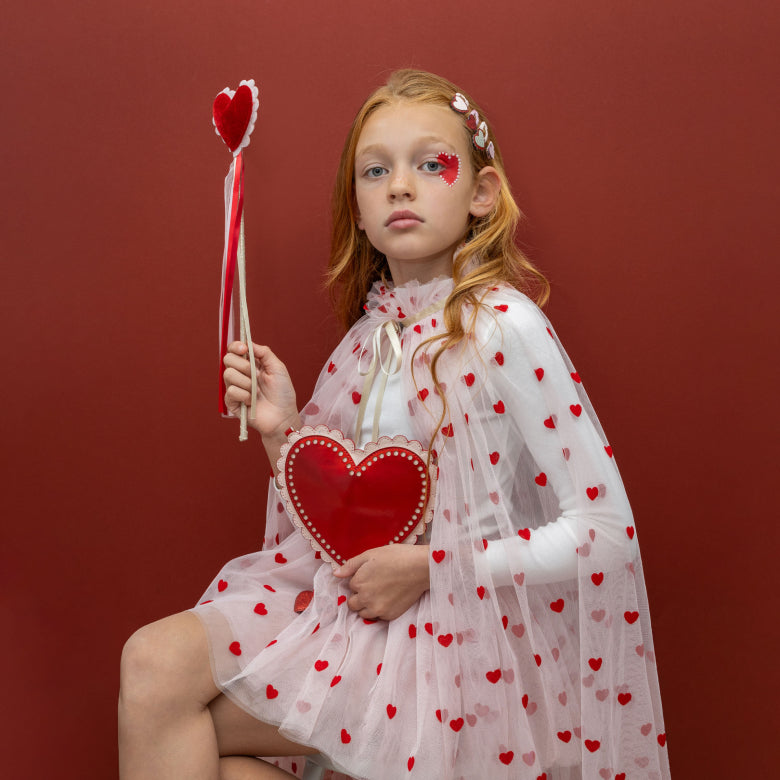 Heart-shaped wand accessory with red, gold, and white ribbons on a white background