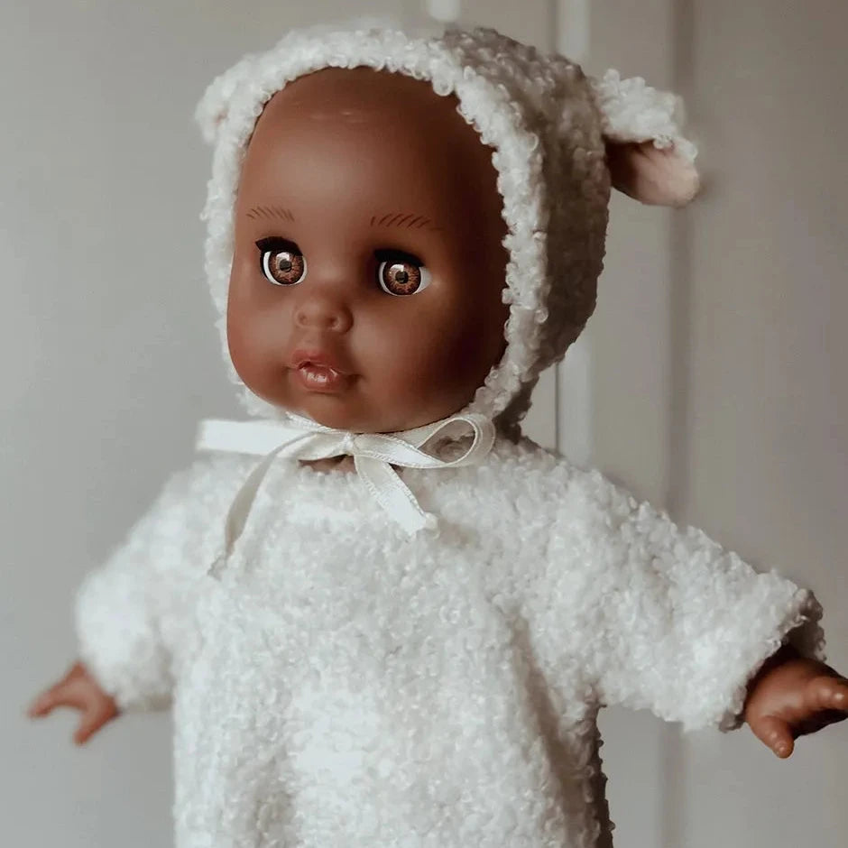 Baby doll wearing a white textured outfit and bonnet against a neutral background