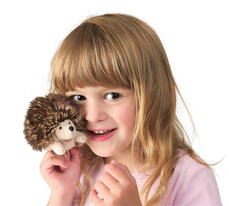 Child holding a hedgehog plush toy against a white background