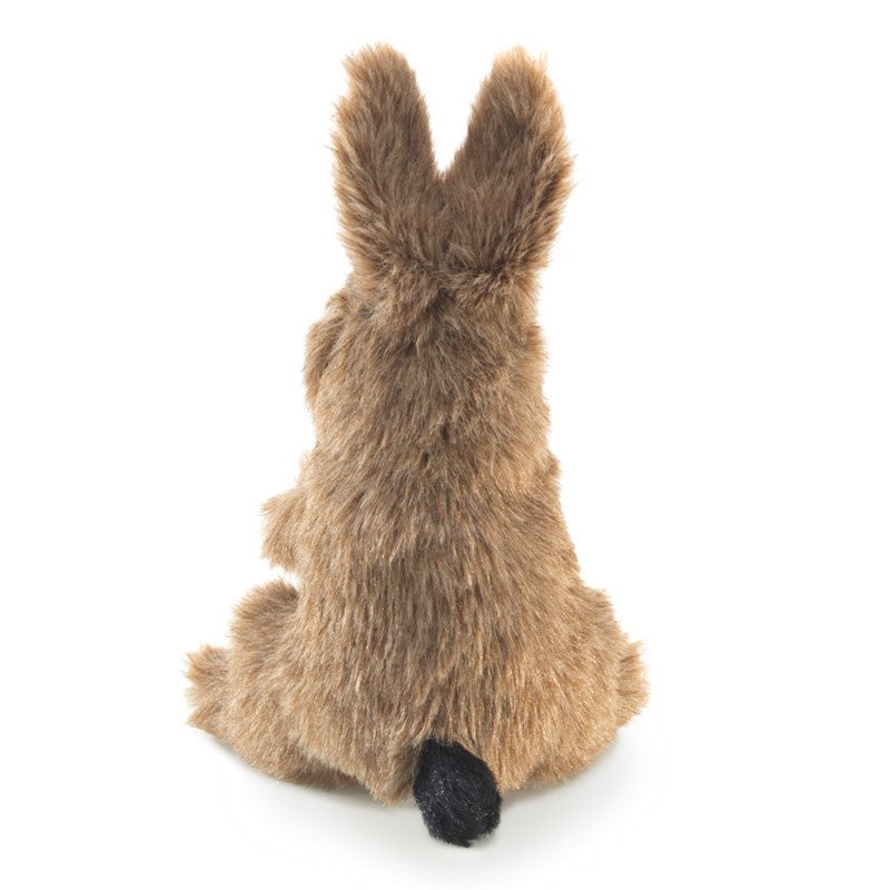 Small brown plush rabbit held in a hand against a white background