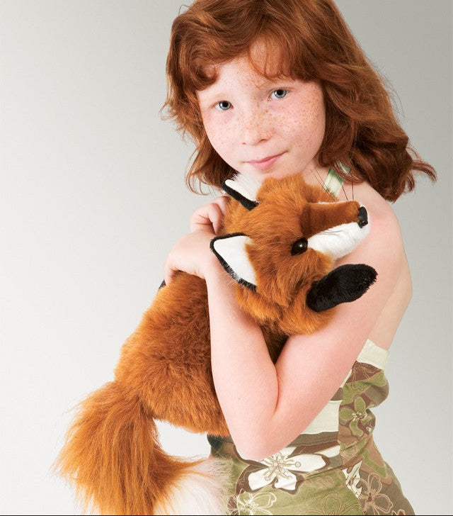 Child holding a plush fox toy against a plain background