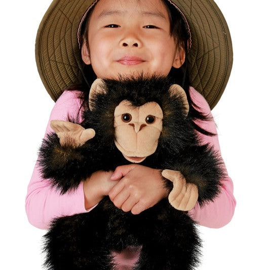 Stuffed monkey toy in a natural setting with plants and rocks