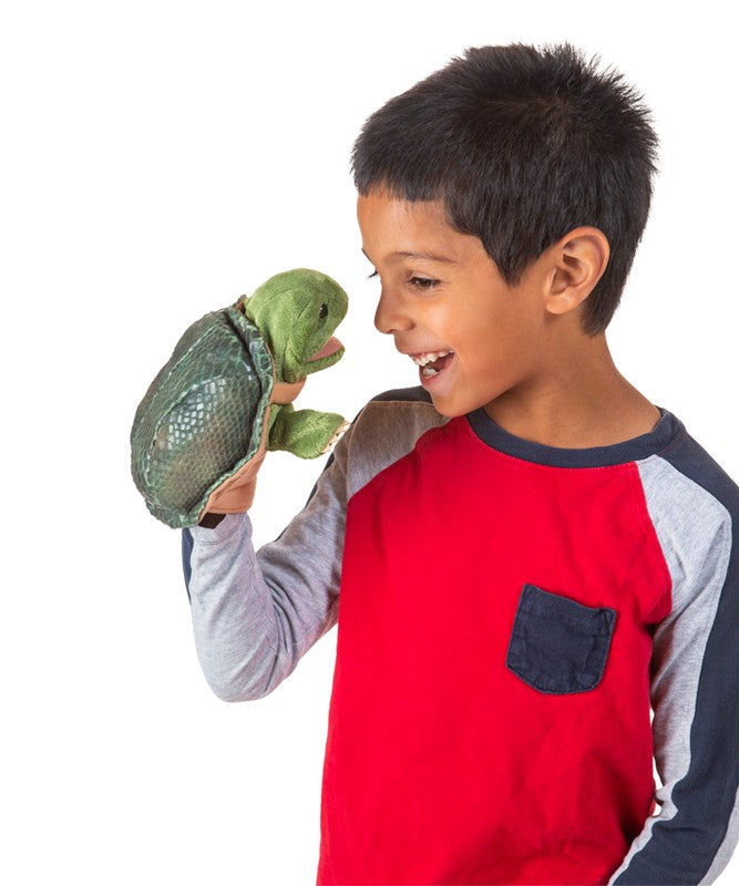 Child holding a green turtle puppet against a white background