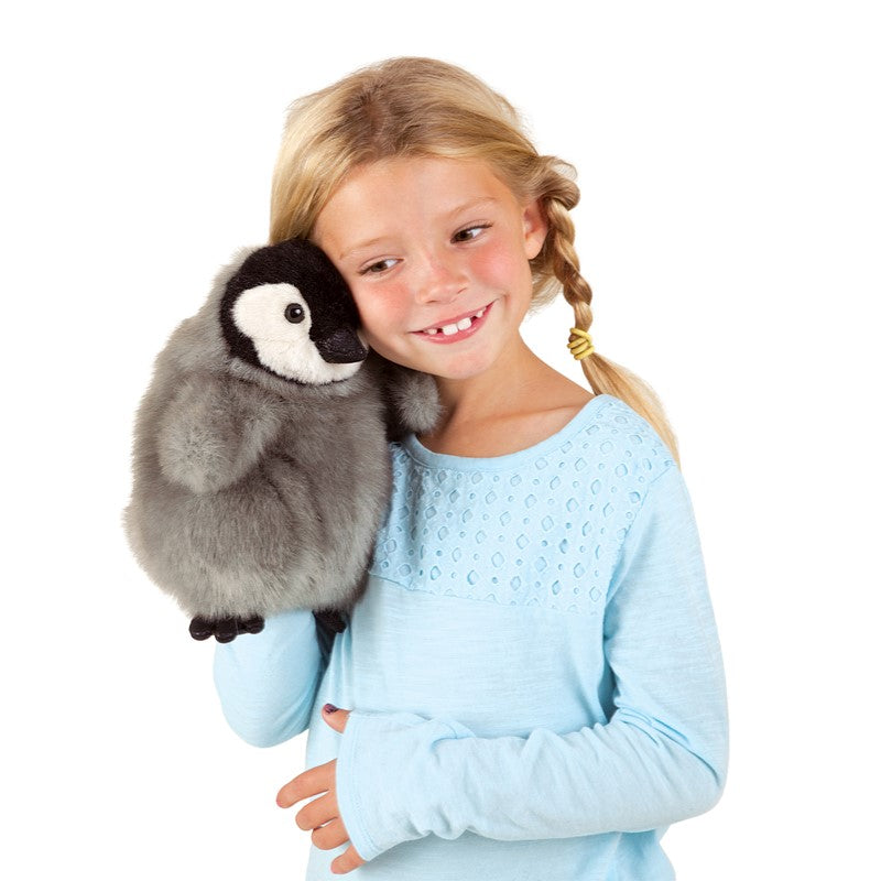Young girl holding a plush penguin toy against a white background