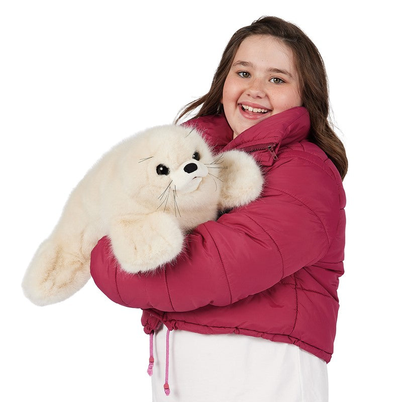 Person wearing a pink jacket holding a plush seal toy on a white background